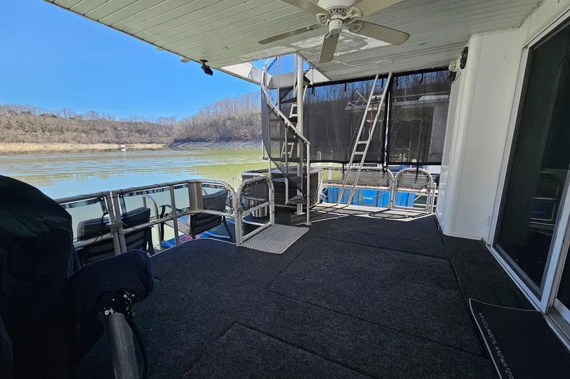 Slide: The Image of 2001 Sumerset 16x79 houseboat deck with lake view, featuring seating and ceiling fan. - 50
