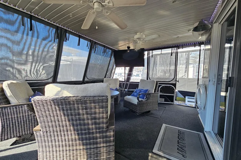 Slide: The Image of Spacious 2001 Sumerset 16x79 houseboat interior with wicker furniture and ceiling fans. - 6