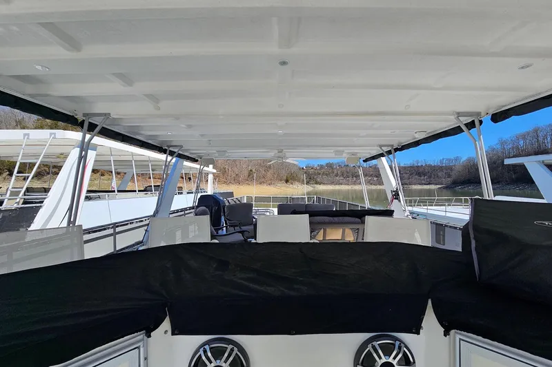 Slide: The Image of 2001 Sumerset 16x79 houseboat interior with seating and covered deck on a calm lake. - 65