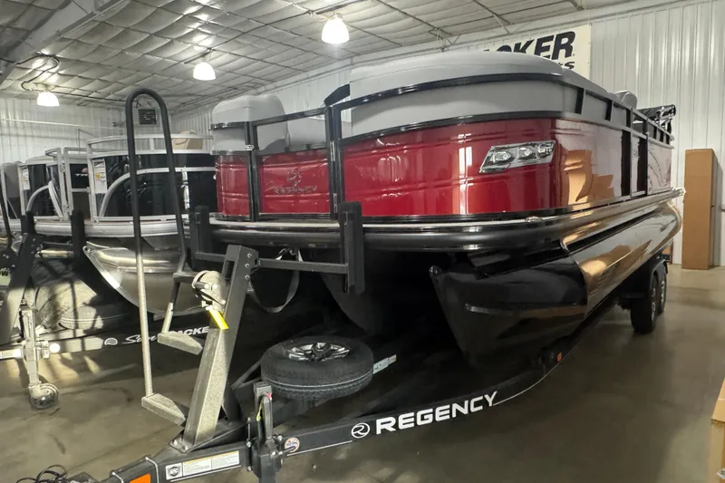 The Image of 2025 Regency 230 DL3 pontoon boat in showroom, featuring sleek red and black design. - 1