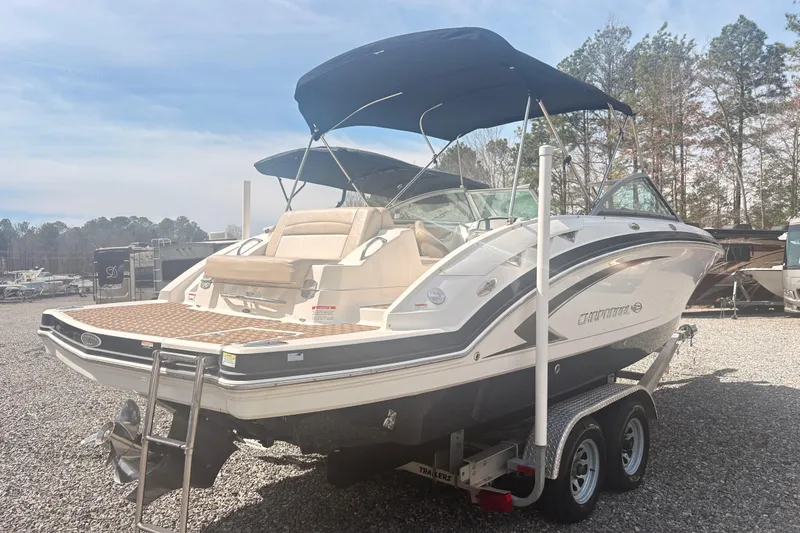 Slide: The Image of 2011 Chaparral 244 Sunesta boat on trailer, parked outdoors with trees in background. - 2