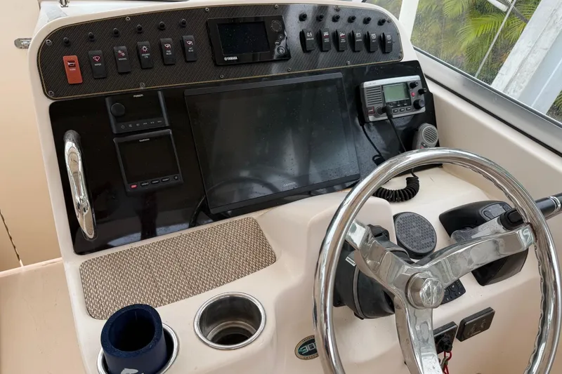 Slide: The Image of Control panel of a 2013 Grady-White Freedom 307 boat with steering wheel and electronics. - 4