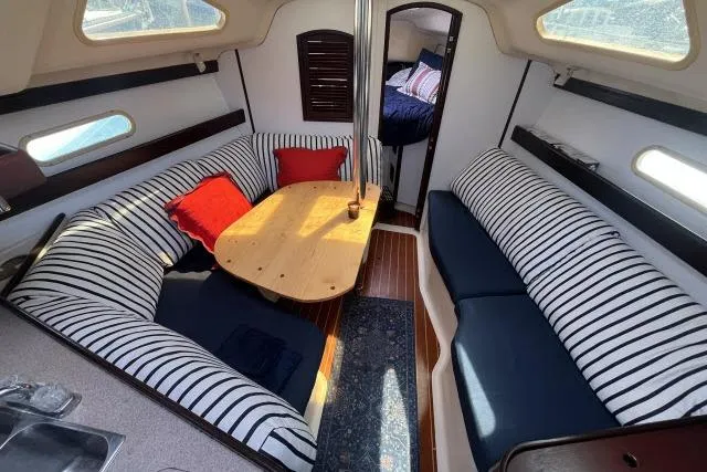 Slide: The Image of Interior of 2000 Hunter 340 sailboat with striped seating and wooden table. - 3