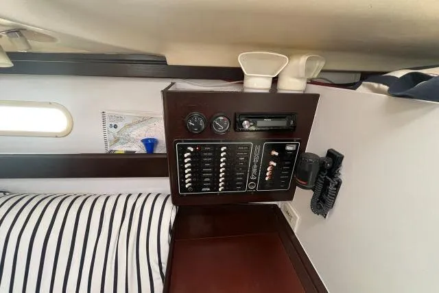 Slide: The Image of Control panel inside a 2000 Hunter 340 sailboat cabin with striped bedding. - 7