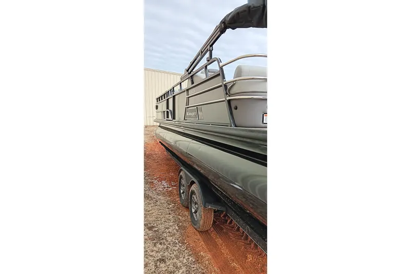 Slide: The Image of 2024 Ranger 2500LS boat on trailer, parked on red dirt near a building. - 11