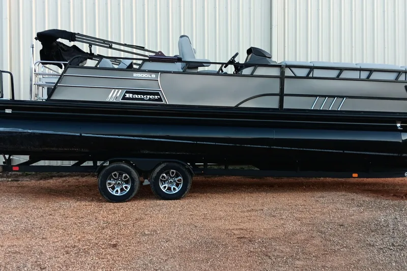Slide: The Image of 2024 Ranger 2500LS pontoon boat on trailer, parked on gravel. - 50