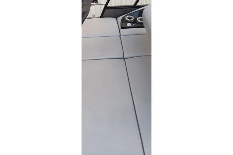 Slide: The Image of 2024 Ranger 2500LS boat interior with gray cushioned seating and cup holders. - 58