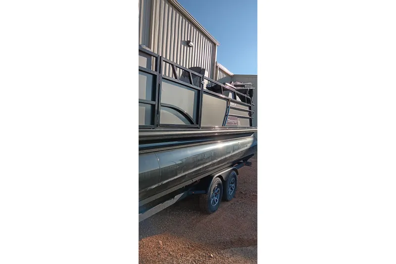 Slide: The Image of 2024 Ranger 2500LS pontoon boat on trailer, parked near a metal building. - 73