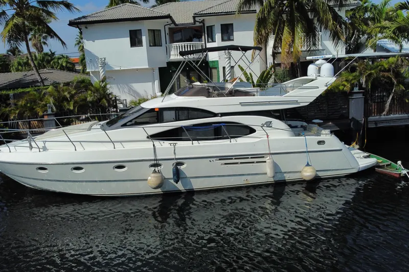 Slide: The Image of 1998 Azimut 52 yacht docked by a waterfront home with palm trees. - 5