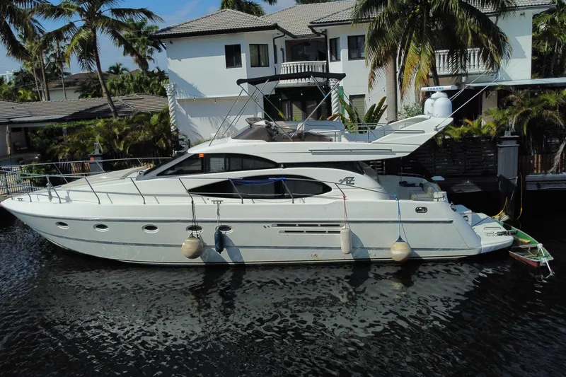 Slide: The Image of 1998 Azimut 52 yacht docked by a waterfront home, surrounded by palm trees. - 6