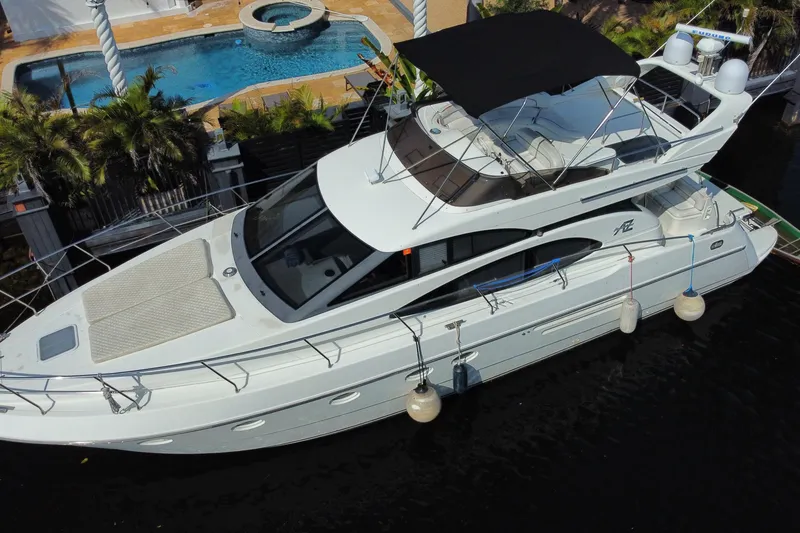 Slide: The Image of 1998 Azimut 52 yacht docked near a pool, featuring a sleek design and flybridge. - 7