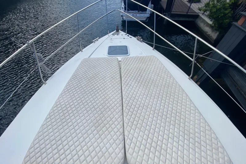 Slide: The Image of Bow view of 1998 Azimut 52 yacht with cushioned deck, docked by water. - 8