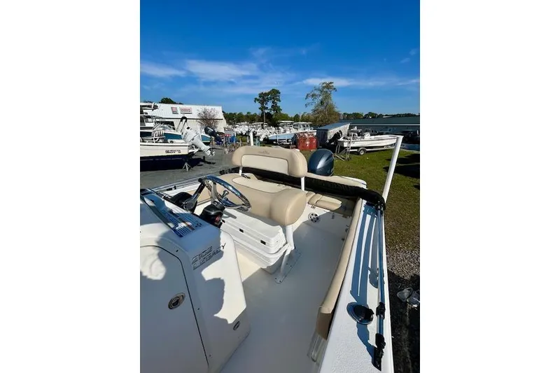 Slide: The Image of 2022 NauticStar 2102 Legacy boat interior with beige seating, parked outdoors. - 6