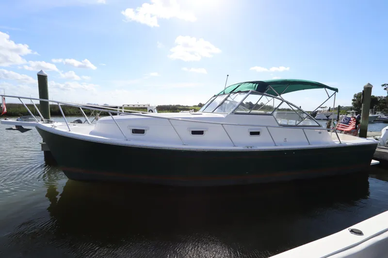 The Image of 2002 Mainship Pilot 34 boat docked, featuring a green canopy and sleek design. - 0