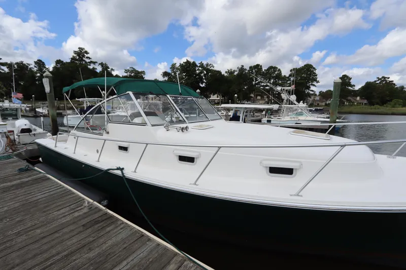 Slide: The Image of 2001 Mainship Pilot 34 docked, featuring a sleek white hull and green canopy. - 3