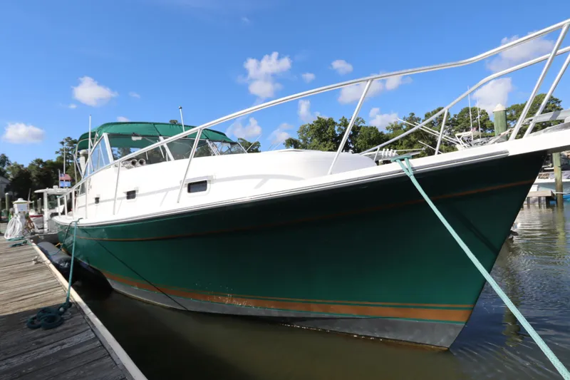 Slide: The Image of 2002 Mainship Pilot 34 docked, green hull, clear sky, calm water. - 4