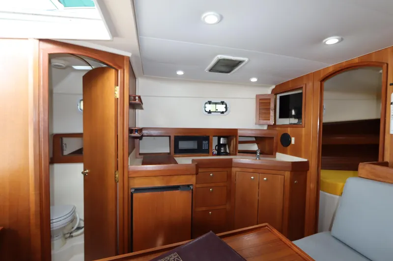 Slide: The Image of 2002 Mainship Pilot 34 interior with kitchenette, wood cabinetry, and seating area. - 43