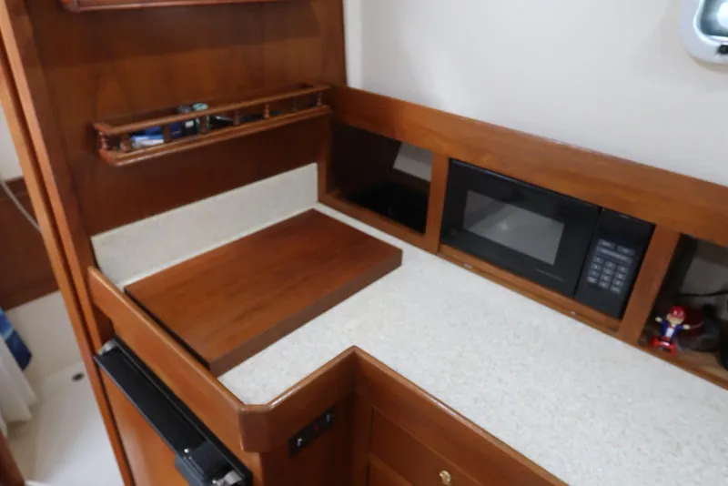 Slide: The Image of 2002 Mainship Pilot 34 galley with wood cabinetry, microwave, and countertop. - 47