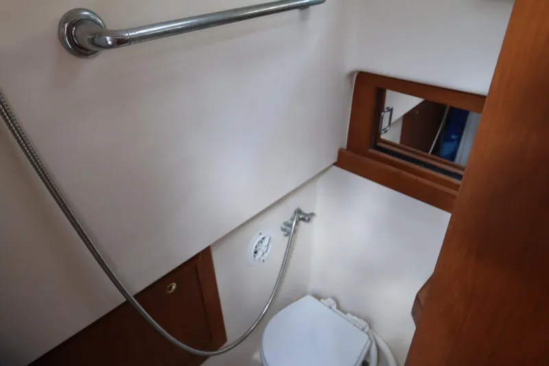 Slide: The Image of 2002 Mainship Pilot 34 boat bathroom with showerhead and wooden accents. - 60