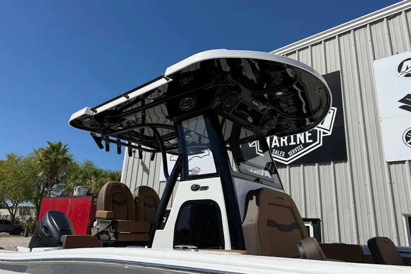 Slide: The Image of 2026 Sea Pro 242 Center Console boat with T-top, parked near a marine service building. - 22