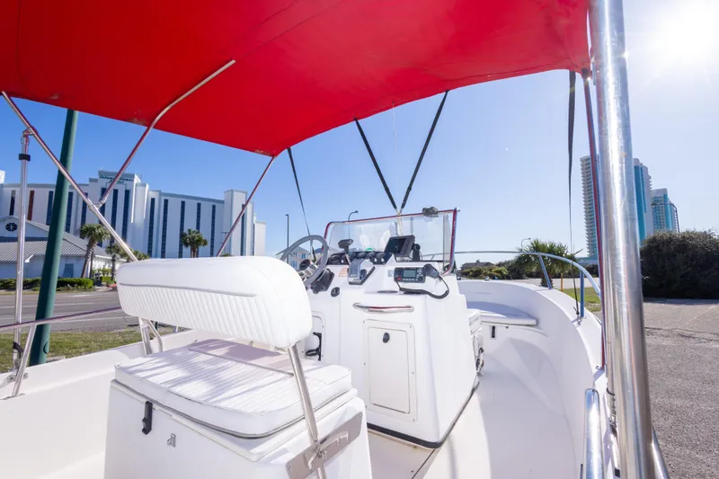 Slide: The Image of 2001 Boston Whaler 18 Dauntless boat interior with red canopy and cityscape background. - 10