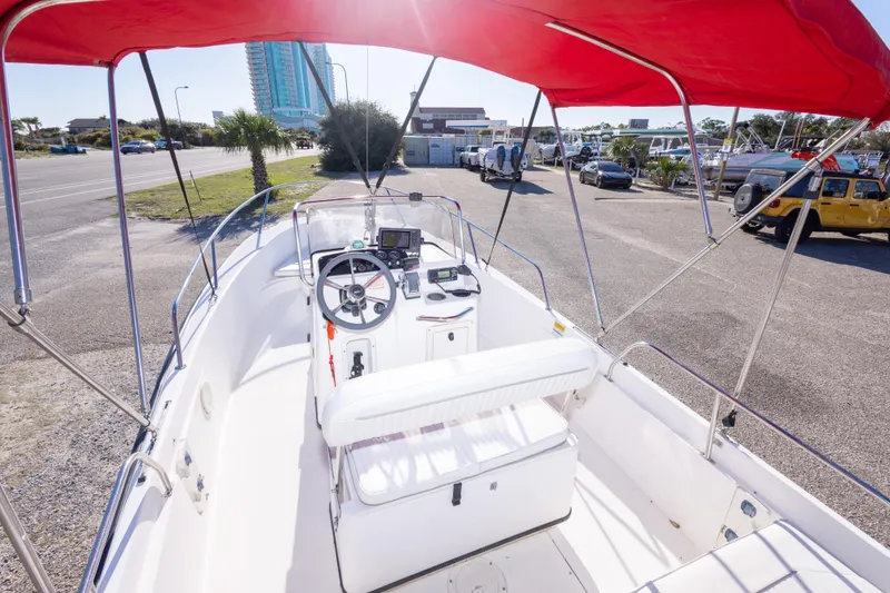 Slide: The Image of 2001 Boston Whaler 18 Dauntless boat with red canopy, parked near a road. - 12