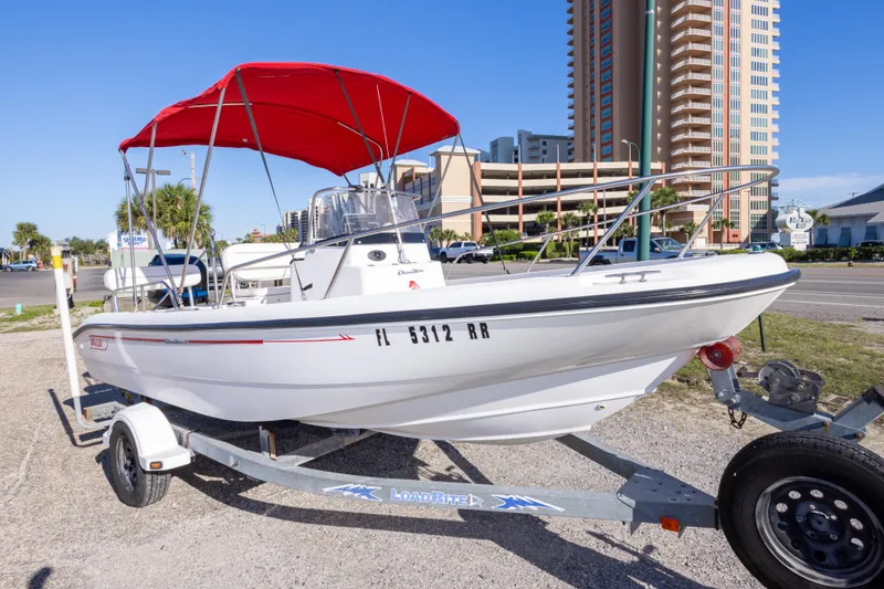 Slide: The Image of 2001 Boston Whaler 18 Dauntless boat with red canopy on trailer, urban background. - 2