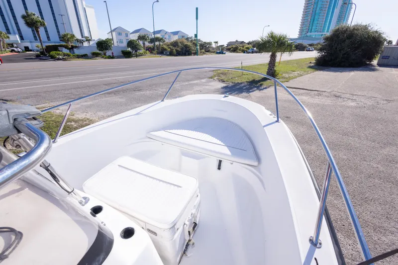 Slide: The Image of 2001 Boston Whaler 18 Dauntless boat parked near a coastal road with buildings. - 20