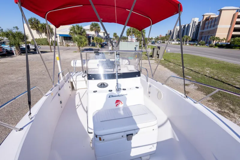 Slide: The Image of 2001 Boston Whaler 18 Dauntless boat with red canopy, parked near a road. - 22