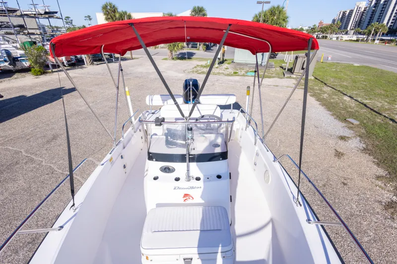Slide: The Image of 2001 Boston Whaler 18 Dauntless boat with red canopy, parked on gravel. - 24