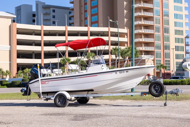 Slide: The Image of 2001 Boston Whaler 18 Dauntless boat with red canopy on trailer, urban background. - 25