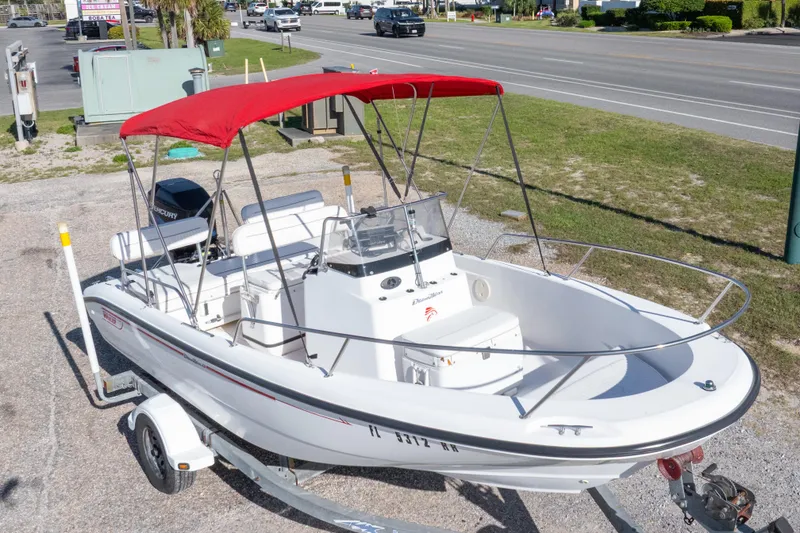 Slide: The Image of 2001 Boston Whaler 18 Dauntless boat with red canopy on trailer, parked near road. - 26