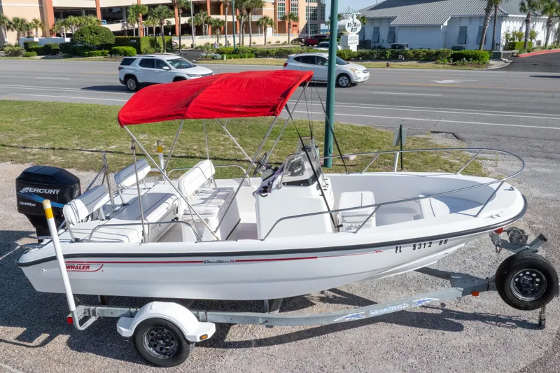 Slide: The Image of 2001 Boston Whaler 18 Dauntless boat with red canopy on trailer, parked roadside. - 27