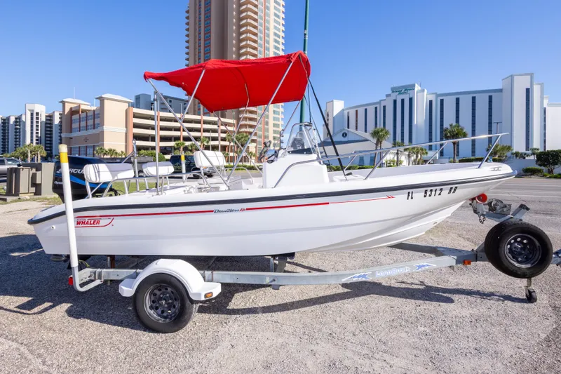 Slide: The Image of 2001 Boston Whaler 18 Dauntless boat with red canopy on trailer, urban background. - 3