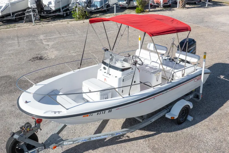 Slide: The Image of 2001 Boston Whaler 18 Dauntless boat with red canopy on trailer, parked outdoors. - 32