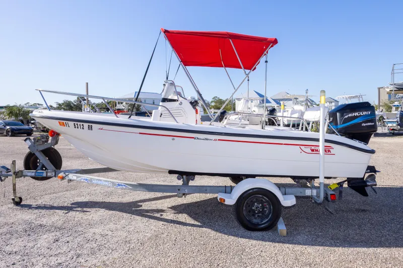 Slide: The Image of 2001 Boston Whaler 18 Dauntless boat with red canopy on trailer, parked outdoors. - 7