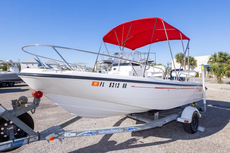 Slide: The Image of 2001 Boston Whaler 18 Dauntless boat with red canopy on trailer in sunny marina. - 8