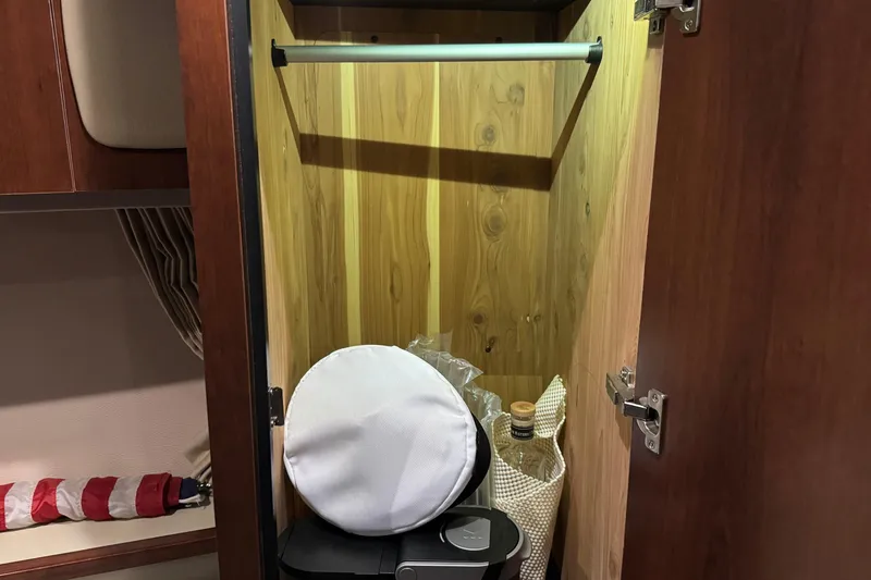 Slide: The Image of Wooden closet interior on 2015 Chaparral 330 Signature boat, with items stored inside. - 25