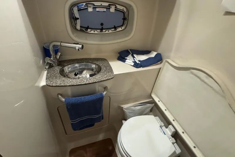Slide: The Image of 2015 Chaparral 330 Signature boat bathroom with sink, toilet, and porthole window. - 26
