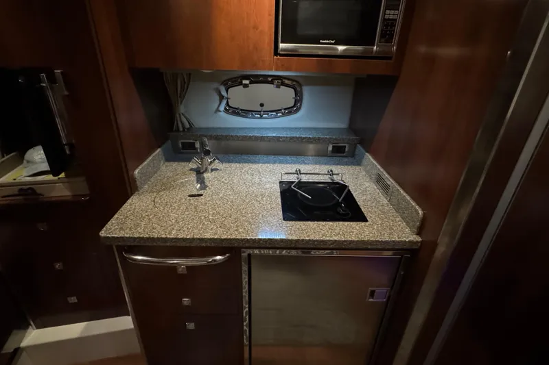 Slide: The Image of 2015 Chaparral 330 Signature yacht kitchen with granite countertop, stove, and microwave. - 28