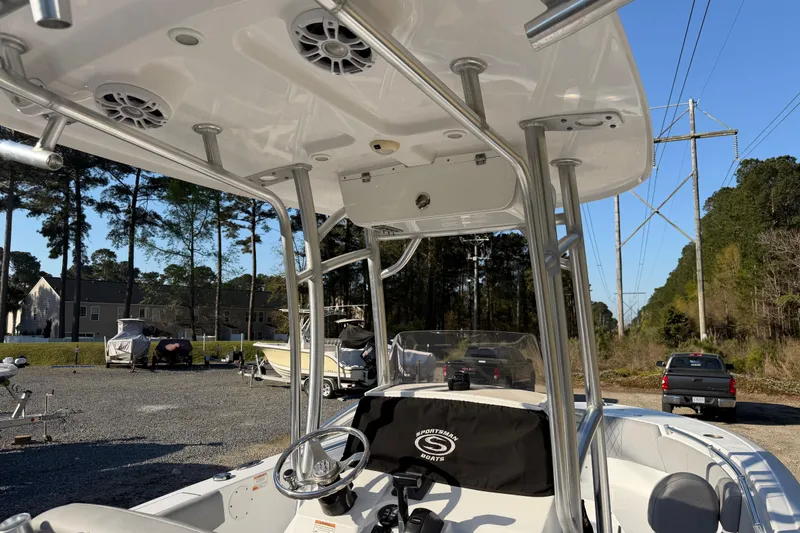 Slide: The Image of 2019 Sportsman Heritage 231 Center Console boat with T-top and speakers, parked outdoors. - 11