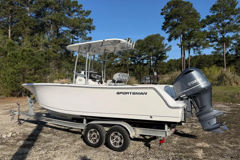 Slide: The Image of 2019 Sportsman Heritage 231 Center Console boat on trailer, surrounded by trees. - 2