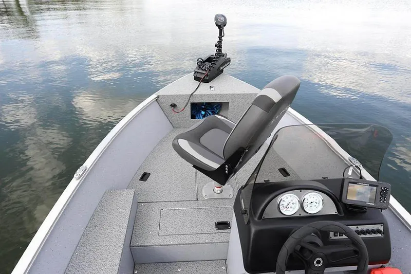 Slide: The Image of Manufacturer Provided Image: 2025 Lund 1600 Fury SS boat interior with steering console and seating on calm water. - 5