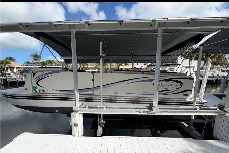 Slide: The Image of 2017 Beachcat 230 boat docked under canopy, side view with water and palm trees. - 19