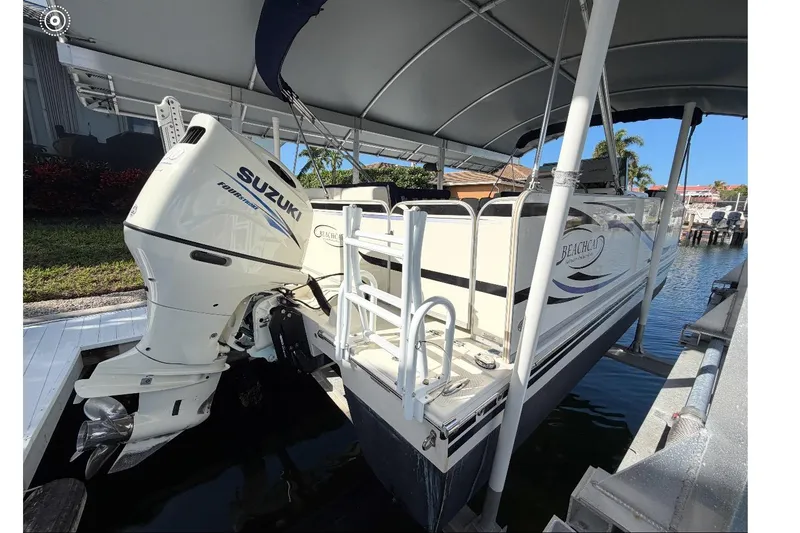 Slide: The Image of 2017 Beachcat 230 boat with Suzuki outboard motor docked under a canopy. - 4