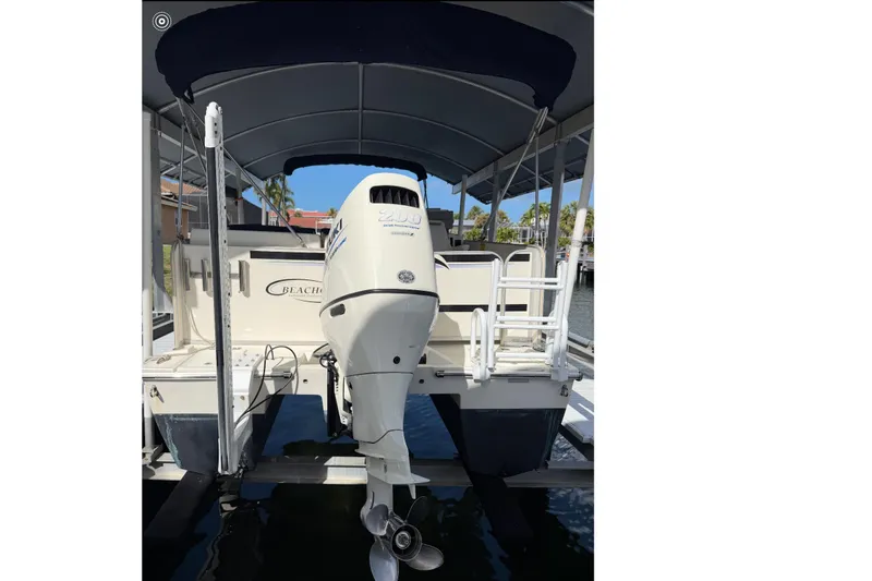 Slide: The Image of 2017 Beachcat 230 boat with outboard motor, docked under a canopy. - 5