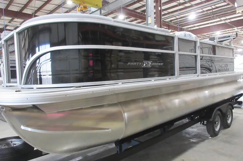 The Image of 2026 Sun Tracker Party Barge 22 DLX pontoon boat in a warehouse setting. - 0