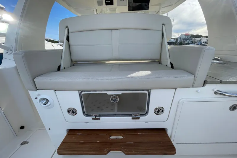 Slide: The Image of 2022 Boston Whaler 350 Realm boat interior with cushioned seating and storage compartment. - 14