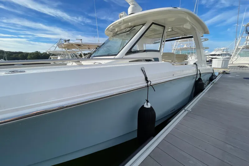 Slide: The Image of 2022 Boston Whaler 350 Realm boat docked in a marina under a blue sky. - 2