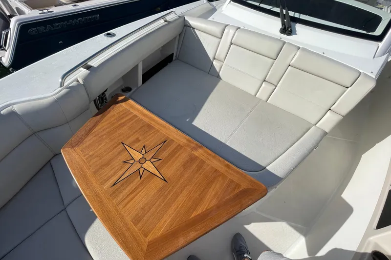 Slide: The Image of Boston Whaler 350 Realm 2022 boat interior with cushioned seating and wooden table. - 31